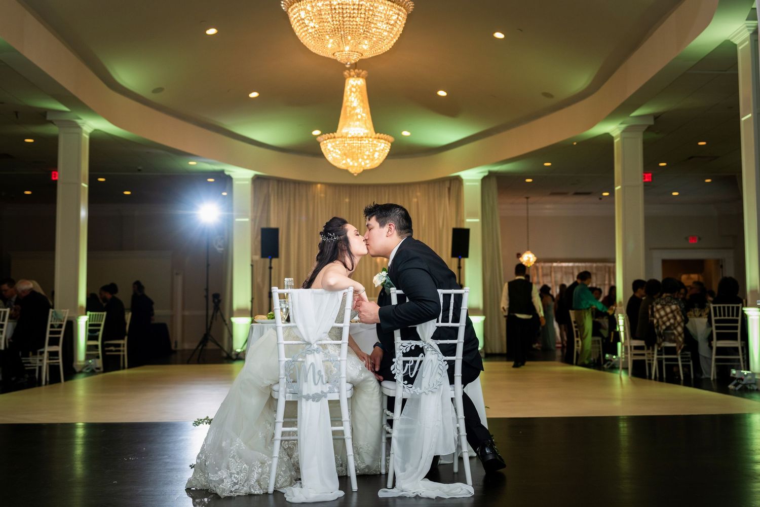 Romantic moment under a grand chandelier in an elegant ballroom reception venue.