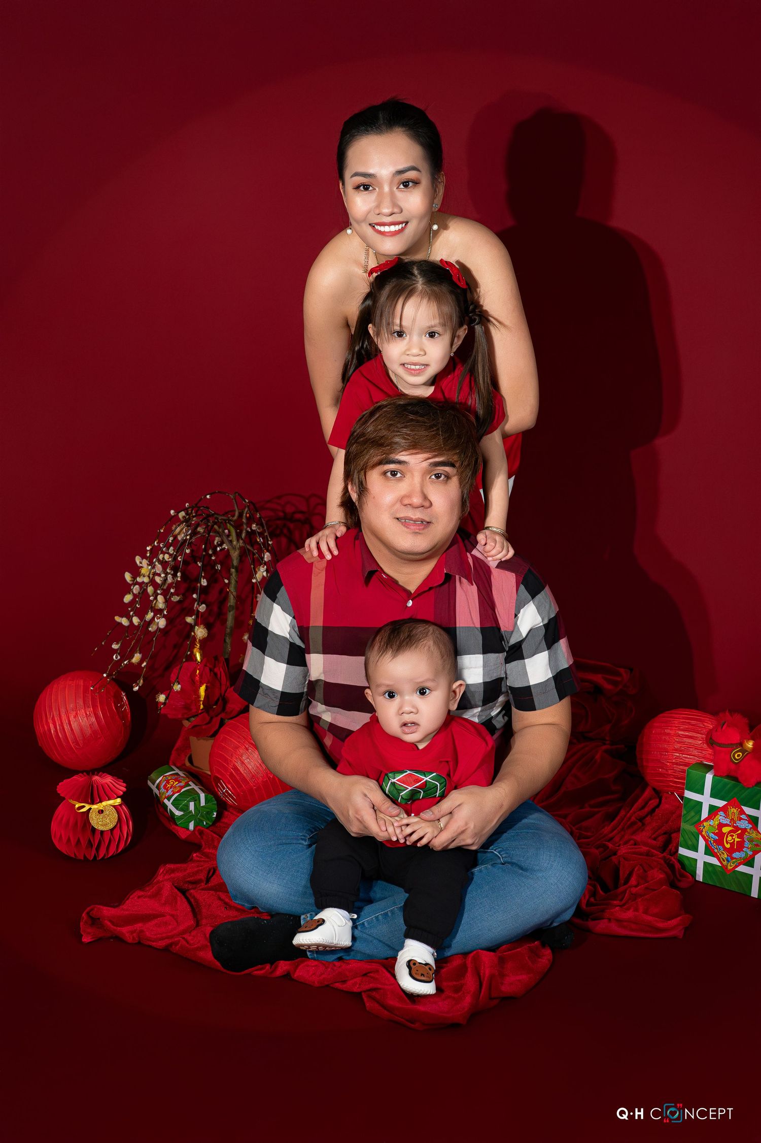 Holiday portrait session with red and black decor featuring festive props and Christmas decorations against burgundy backdrop.