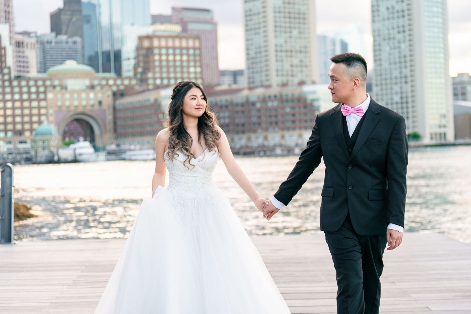 A couple in wedding attire shares intimate moments against a city skyline backdrop.
