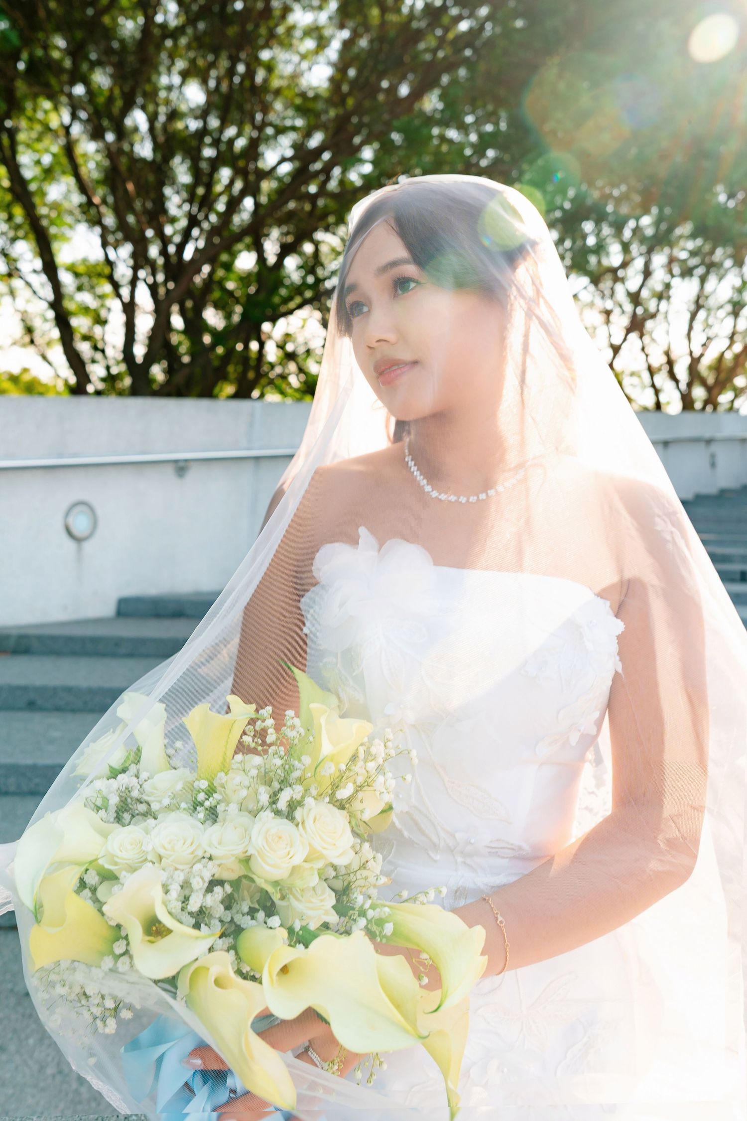 Sun-drenched outdoor bridal portraits featuring a classic white dress and yellow orchid bouquet.