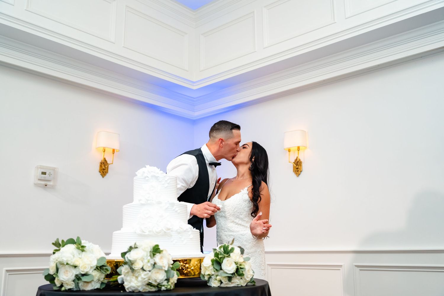 Elegant white wedding reception room with crystal chandelier and romantic lighting.