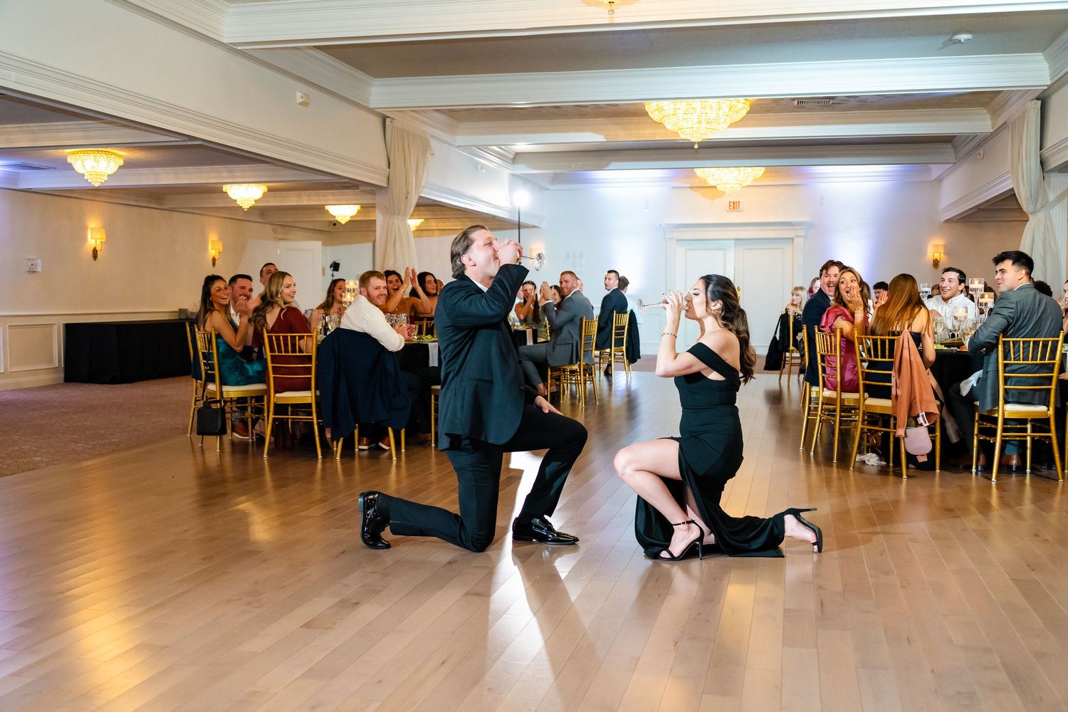 Panoramic view of an elegant wedding reception venue with chandeliers and hardwood floors.