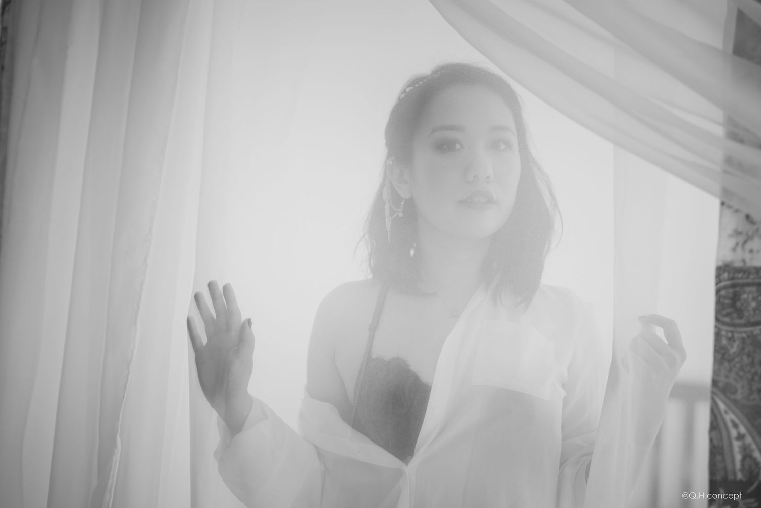 Ethereal bridal portrait through sheer white curtains in black and white photography.