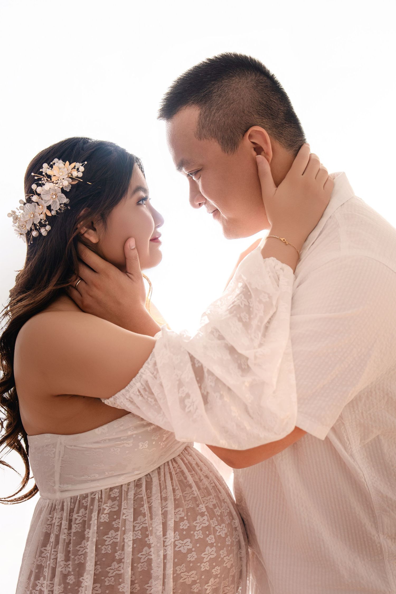 Bright and airy maternity portraits in white outfits showing tender moments between couple.