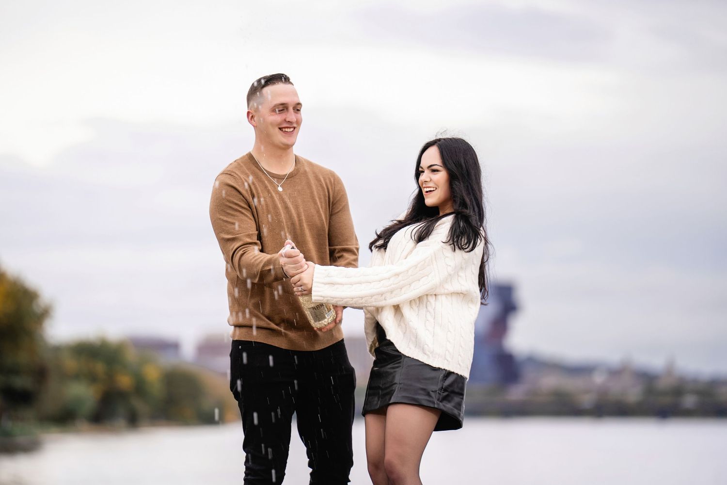 A couple shares a romantic moment together outdoors against a cloudy sky.