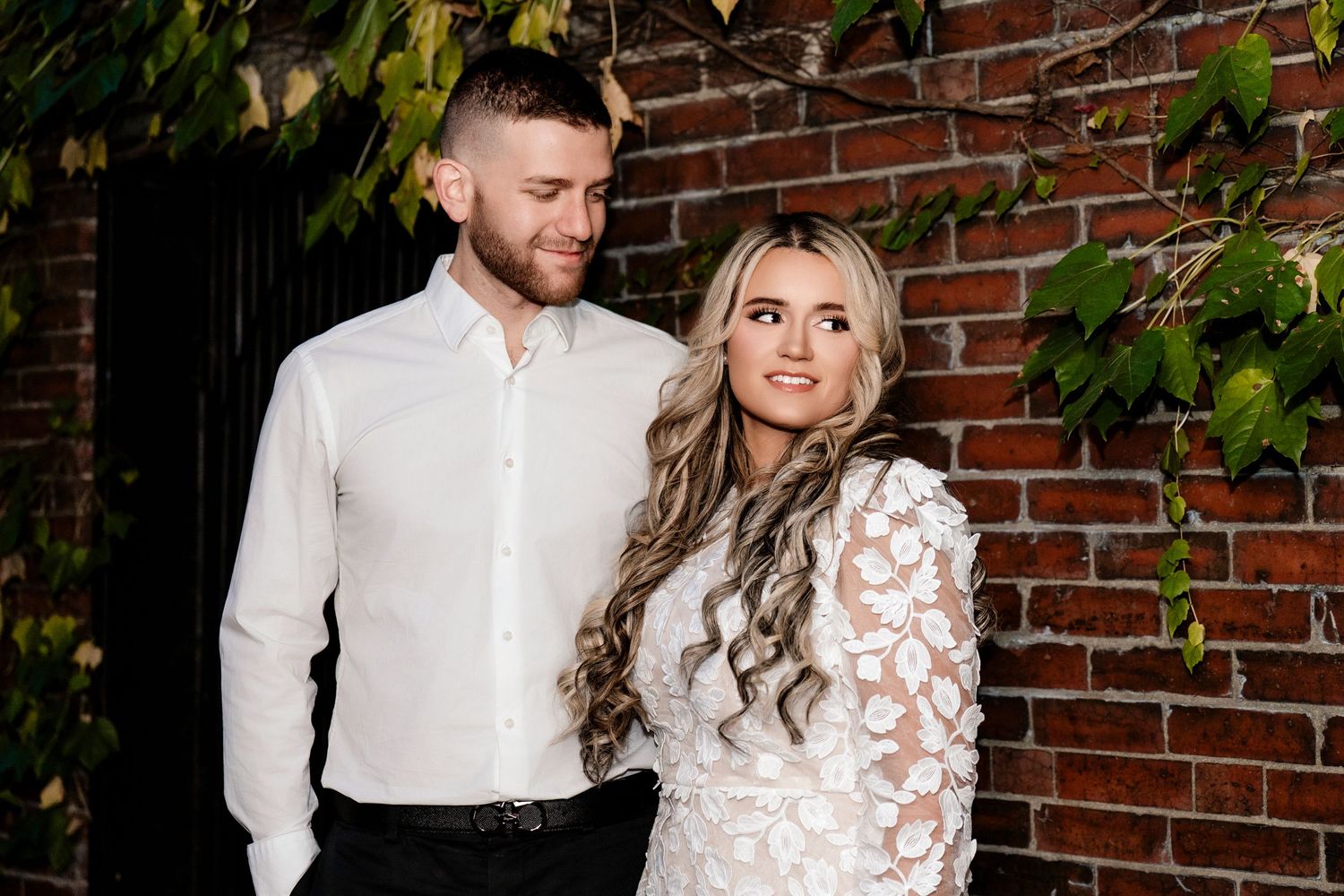 Romantic couple portraits against rustic brick wall with climbing vines.