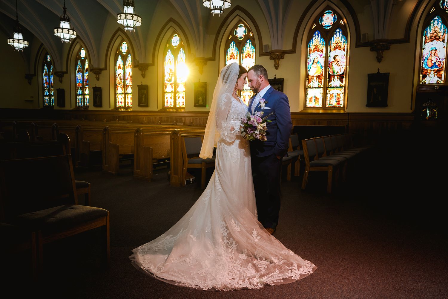 Gothic church interior with stained glass windows and arched ceilings during a wedding ceremony.