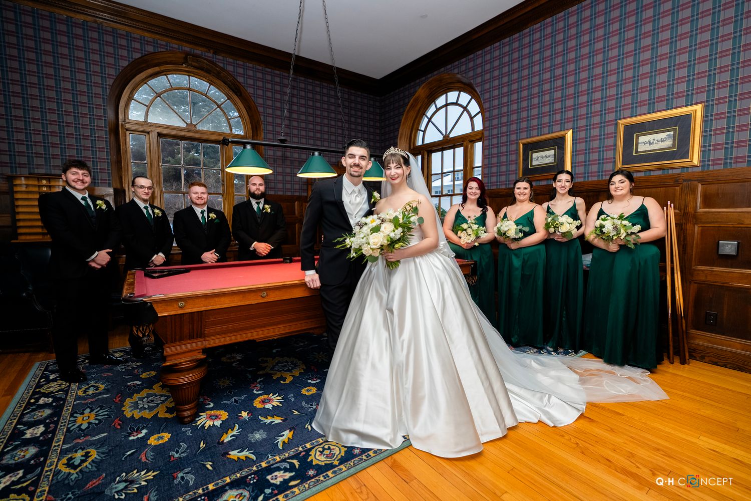Wedding party poses in formal attire in a room with pool table and vintage decor.
