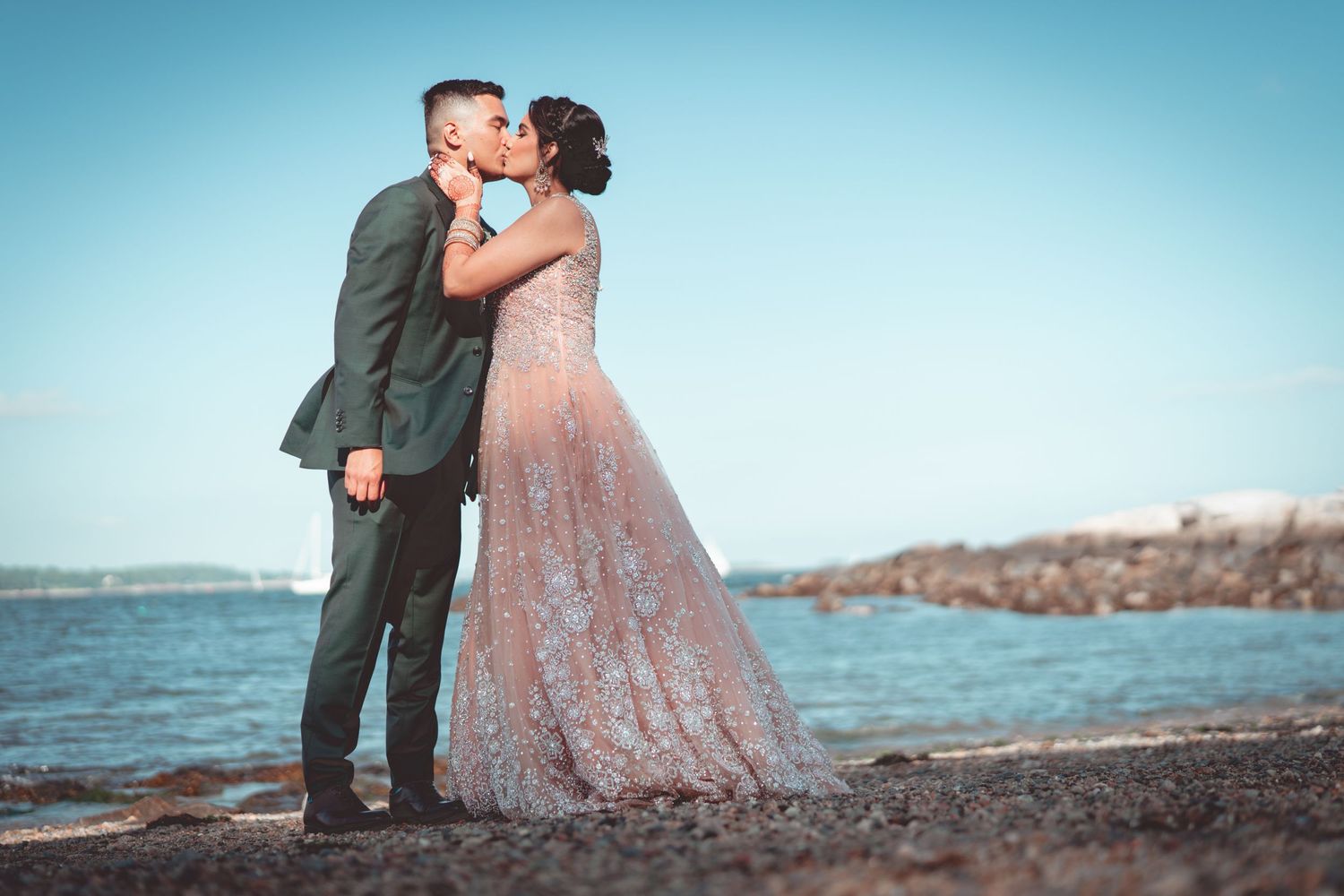 A romantic seaside portrait with a flowing pink gown against blue sky.