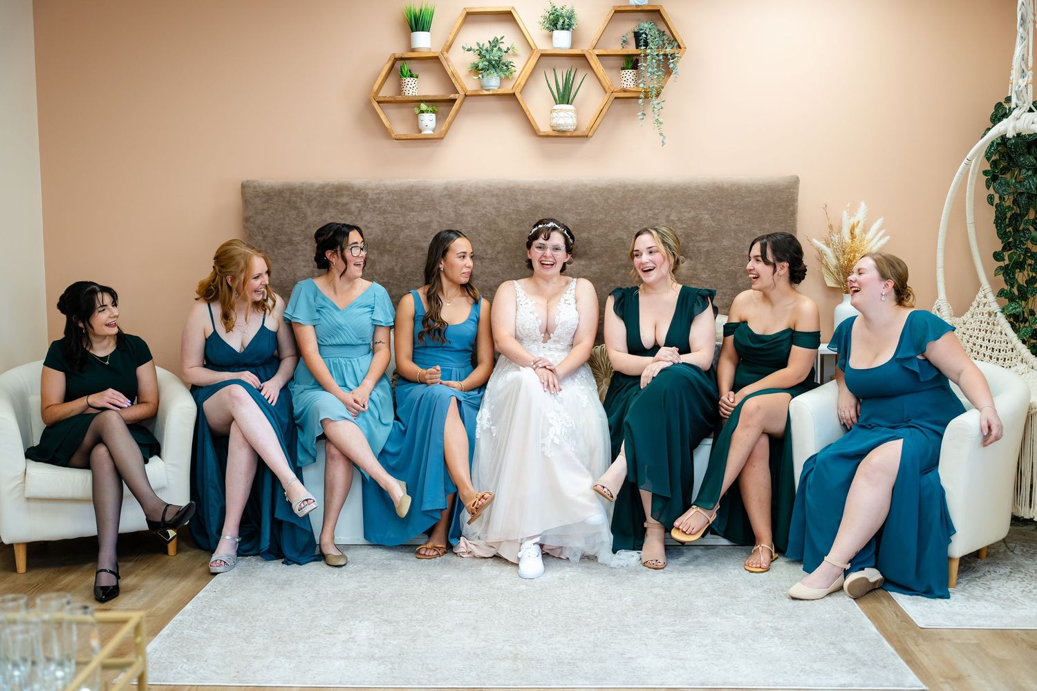 Bridal party relaxing on couch in coordinated blue dresses with geometric wall decor.