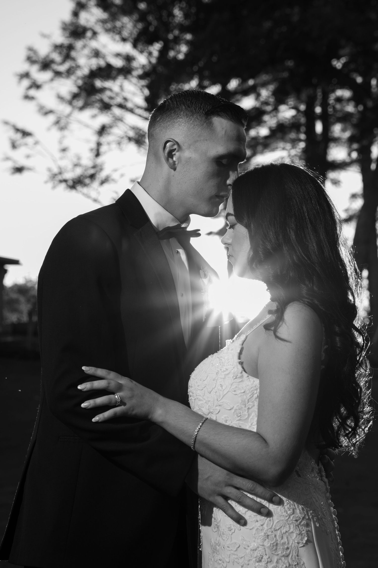 Silhouetted couple sharing romantic kisses against sunlit forest backdrop.