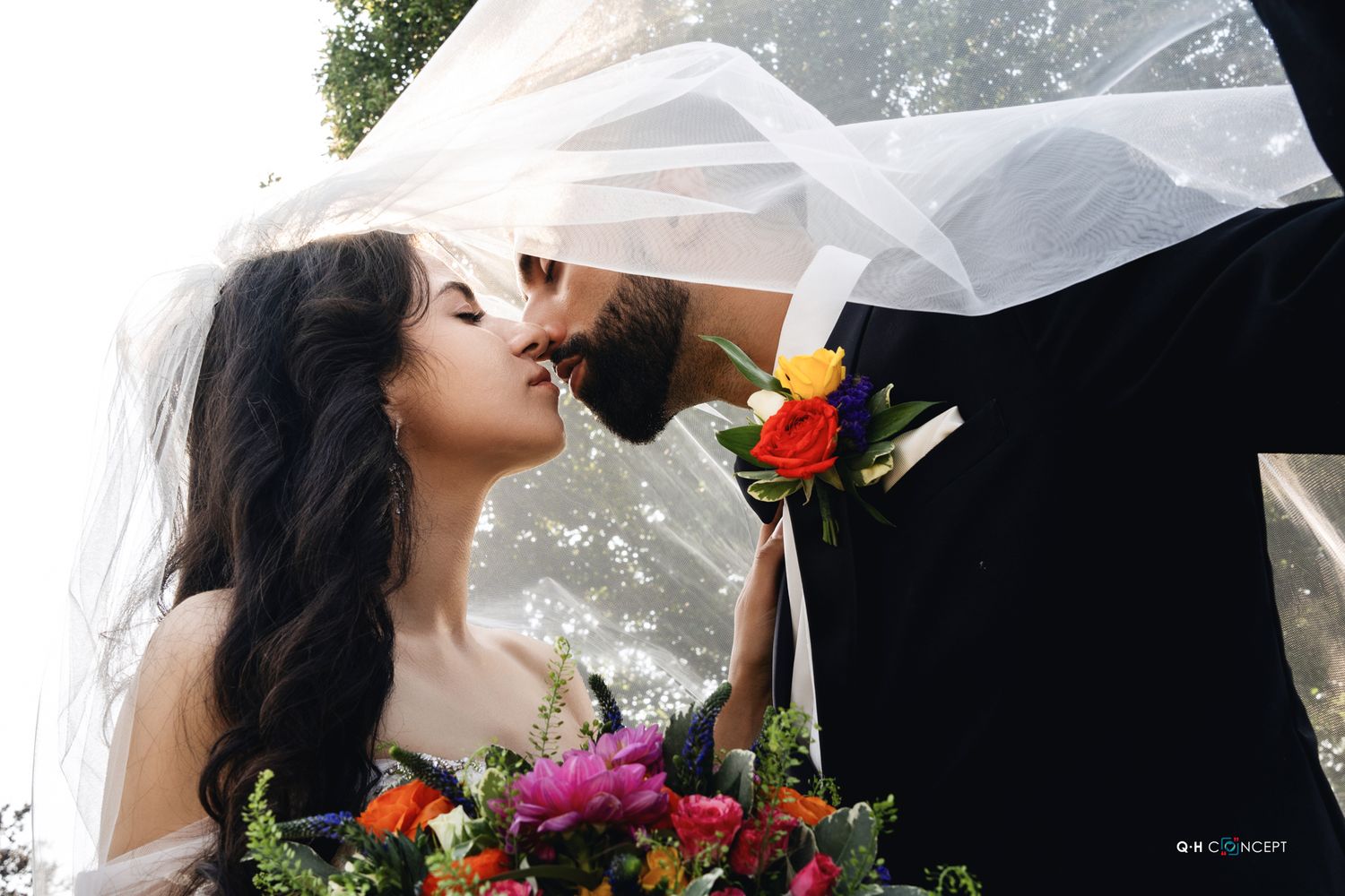 White umbrella frames romantic moment with colorful bouquet details.