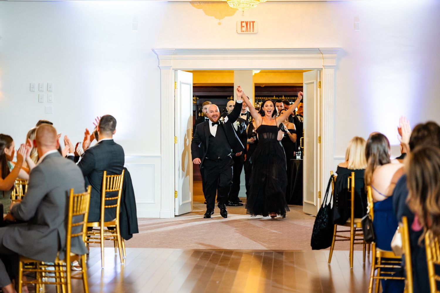 Wedding guests dance and celebrate together on a white dance floor at an elegant indoor reception venue.