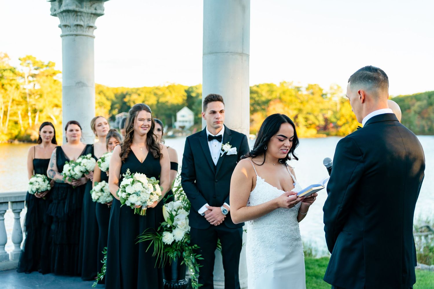 Wedding party gathered under white pillars during an outdoor autumn ceremony.