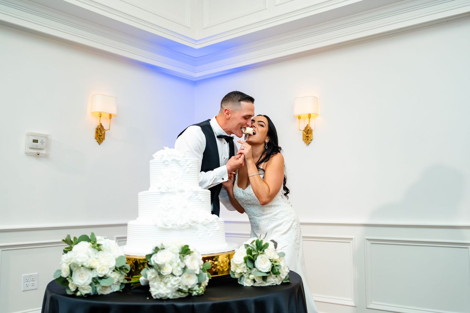 Elegant white and gold wedding reception venue with romantic lighting and floral centerpieces.