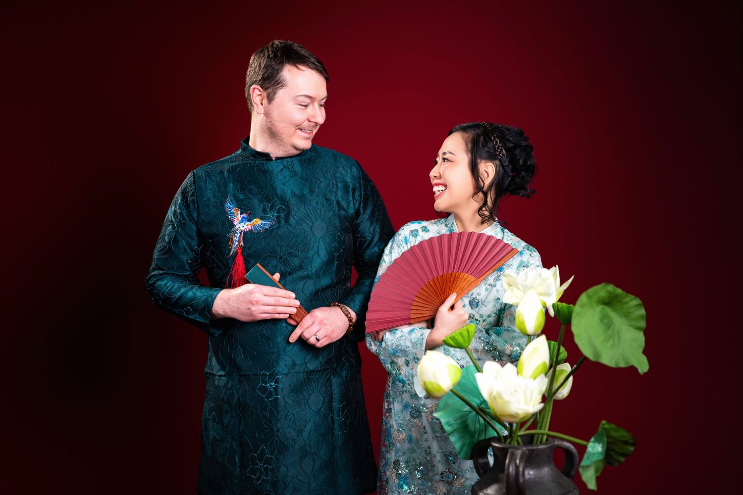 Two performers in traditional Chinese clothing interact during a theatrical performance against a deep red background.
