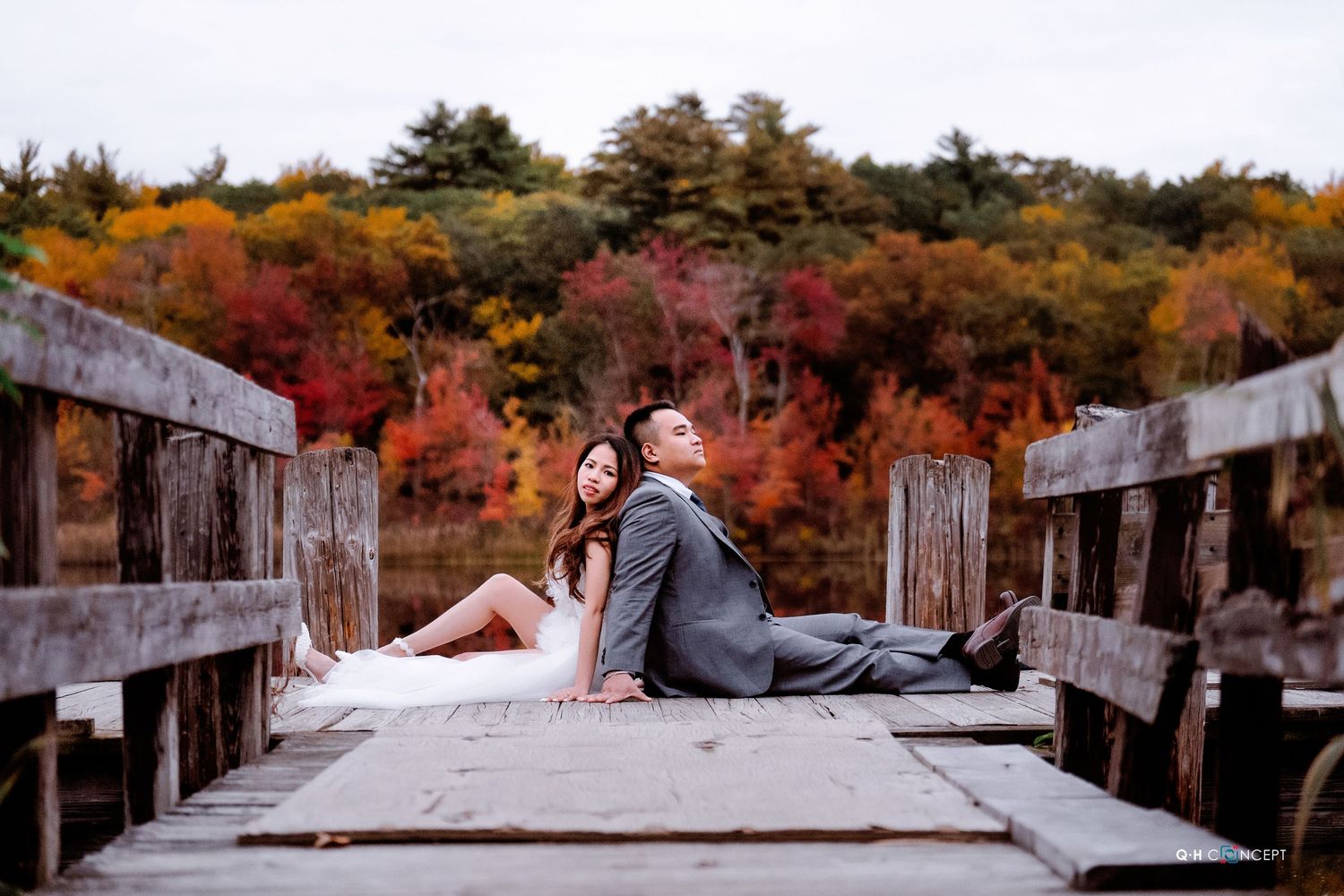 A couple relaxes on concrete steps surrounded by vibrant fall foliage.