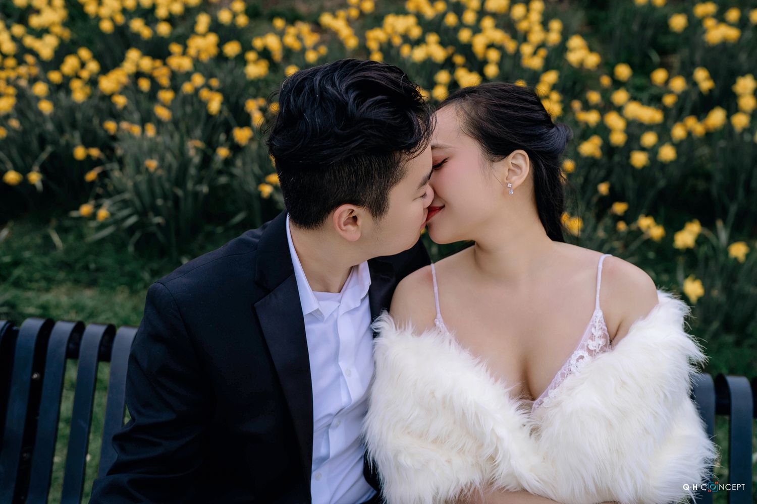 Romantic couple sharing intimate moments in a garden with yellow flowers blooming in the background.