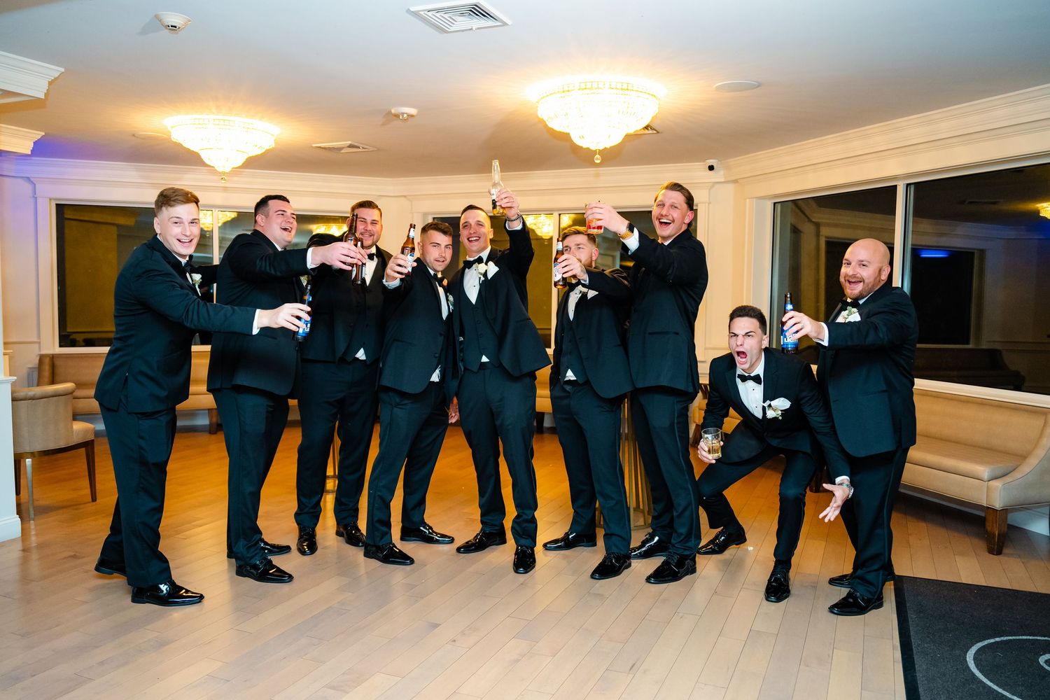 Wedding party members in formal attire gather for group photos in an elegant venue.