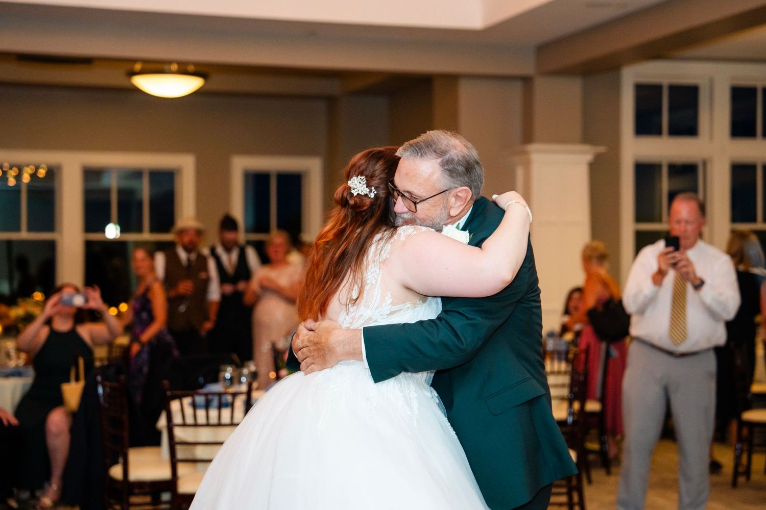 Couples dance together during a joyful wedding celebration in a brightly lit venue.