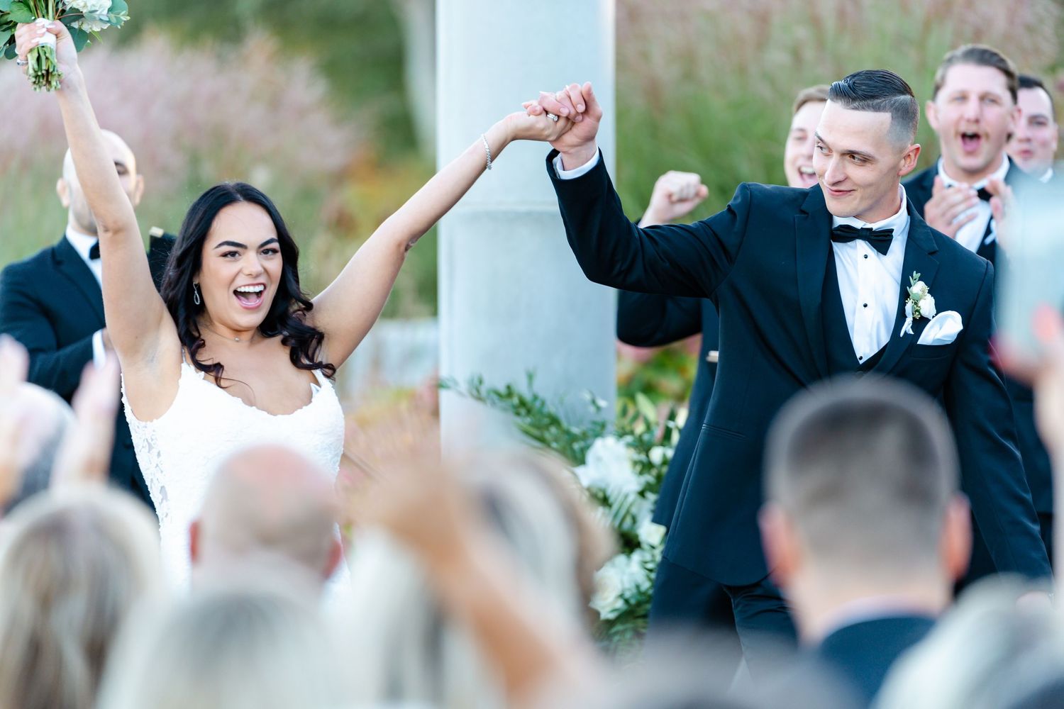 Wedding celebration with guests cheering during outdoor ceremony.