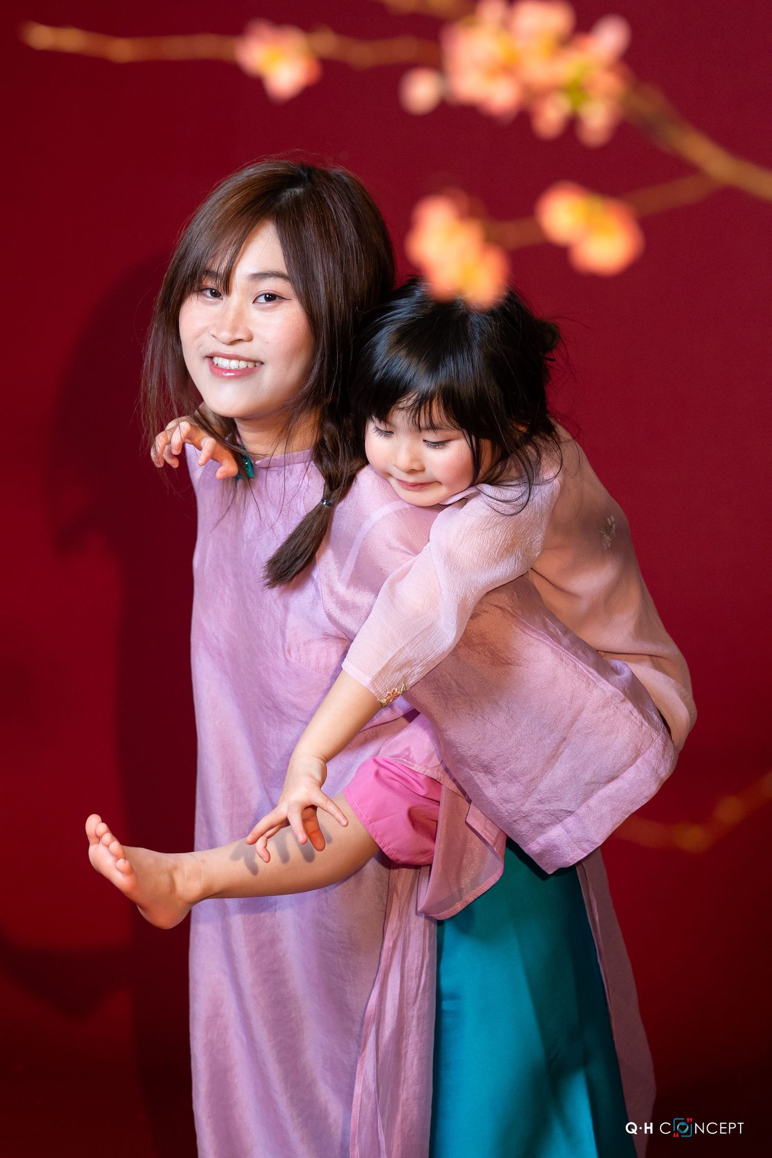 Two dancers in pink and teal outfits perform an expressive contemporary dance sequence against a deep red background.