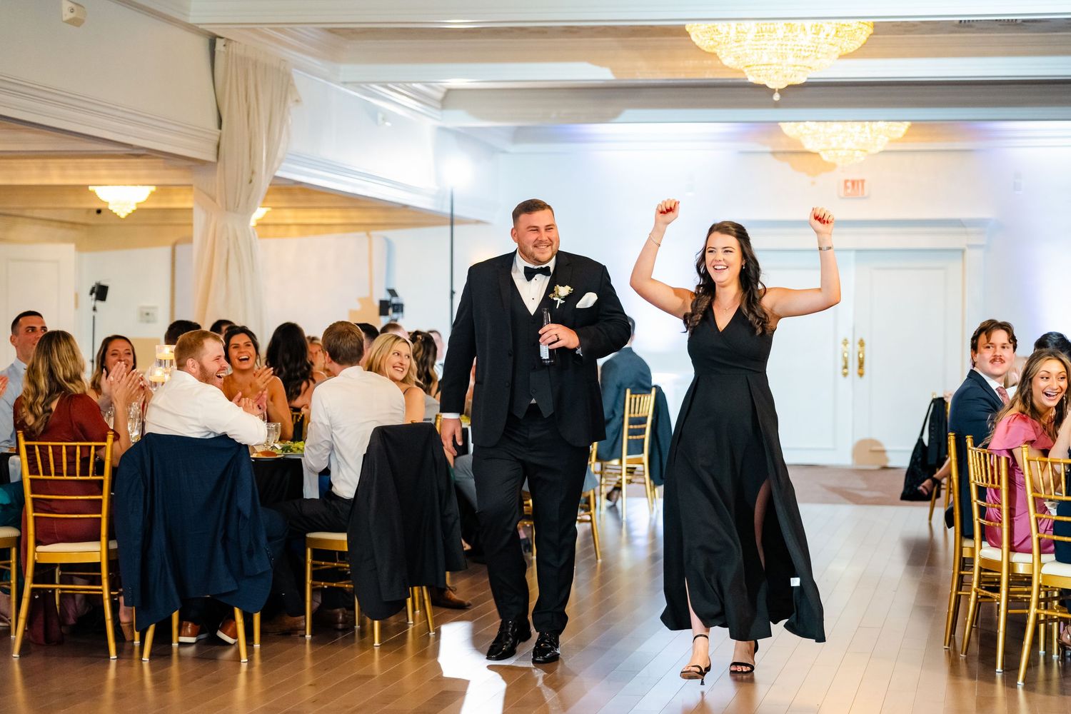 Wedding party celebrating on the dance floor in a brightly lit ballroom.