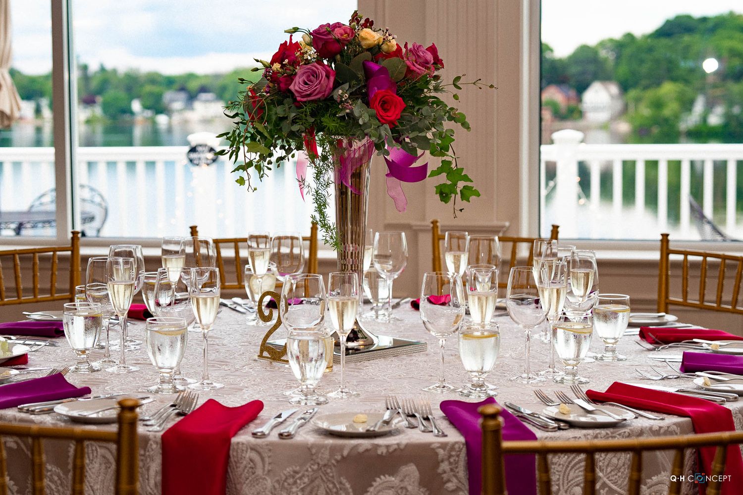 Elegant wedding reception tables set with pink accents, white linens, and crystal glassware in a bright banquet room.