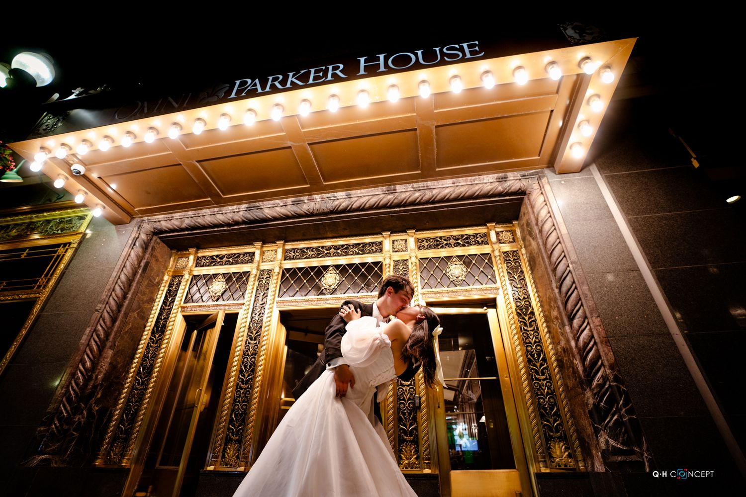 Illuminated marquee lights of Parker House create a dramatic backdrop for a wedding scene.