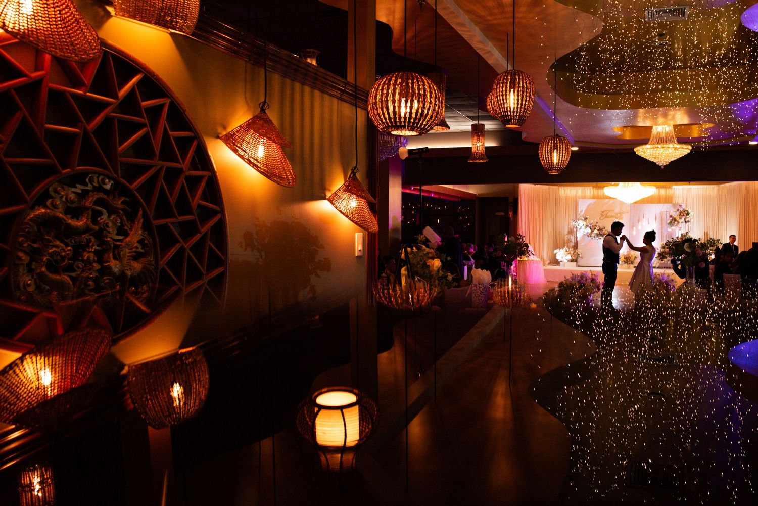 Warm glowing lanterns and string lights create an intimate ambiance at an evening wedding reception venue.