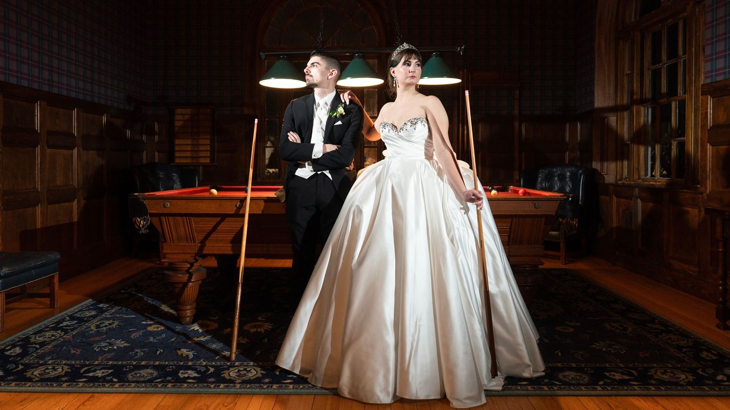 A bride in a flowing white gown walks through a dimly lit hallway with dramatic lighting and shadows.
