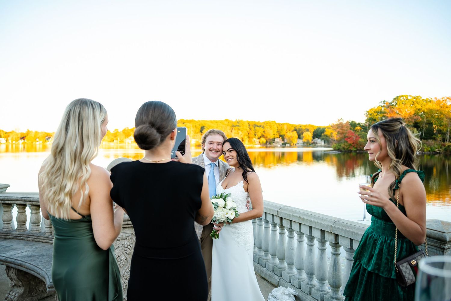 Group of wedding guests gathered on a balcony during sunset.