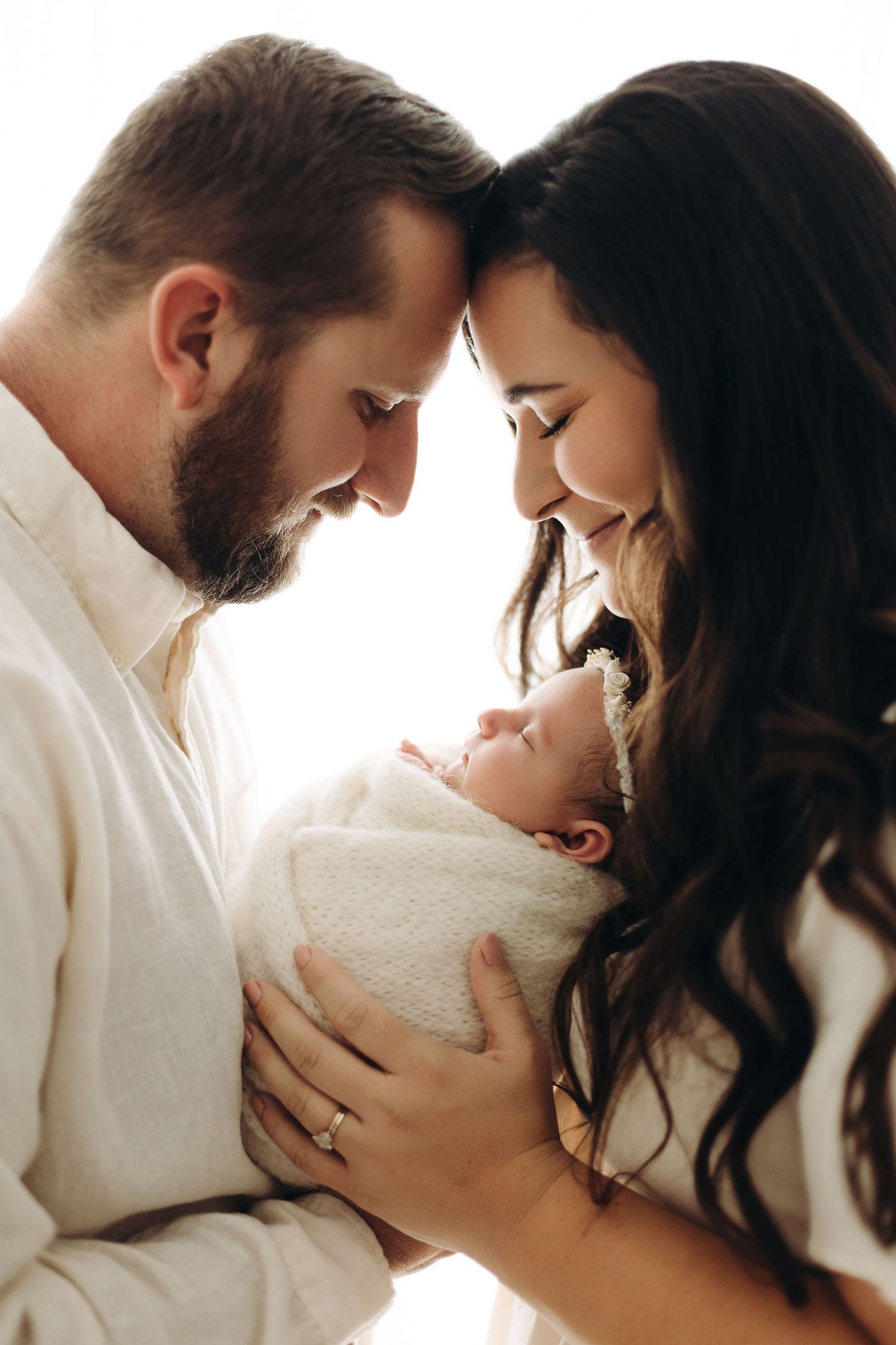 A romantic couple shares intimate close up moments in a white minimalist setting across a series of connected photos.