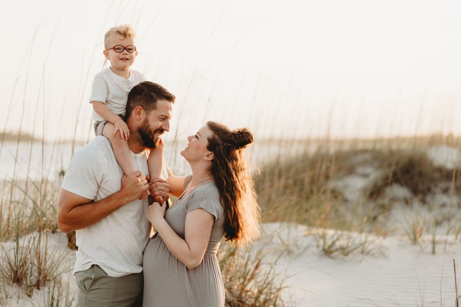 Family shares joyful moment together on beach during golden hour photoshoot.