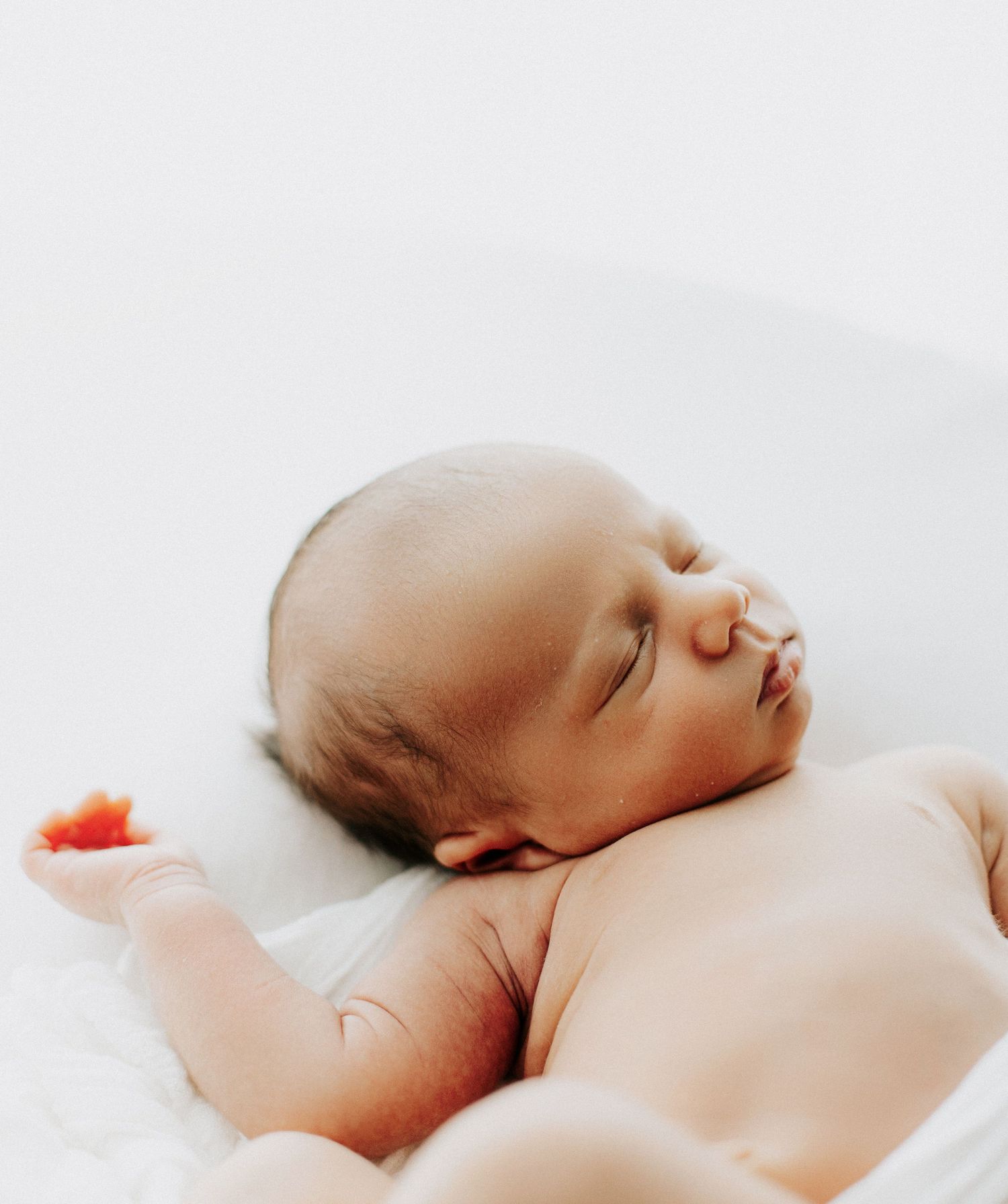 Side view of sleeping newborn baby on white background.