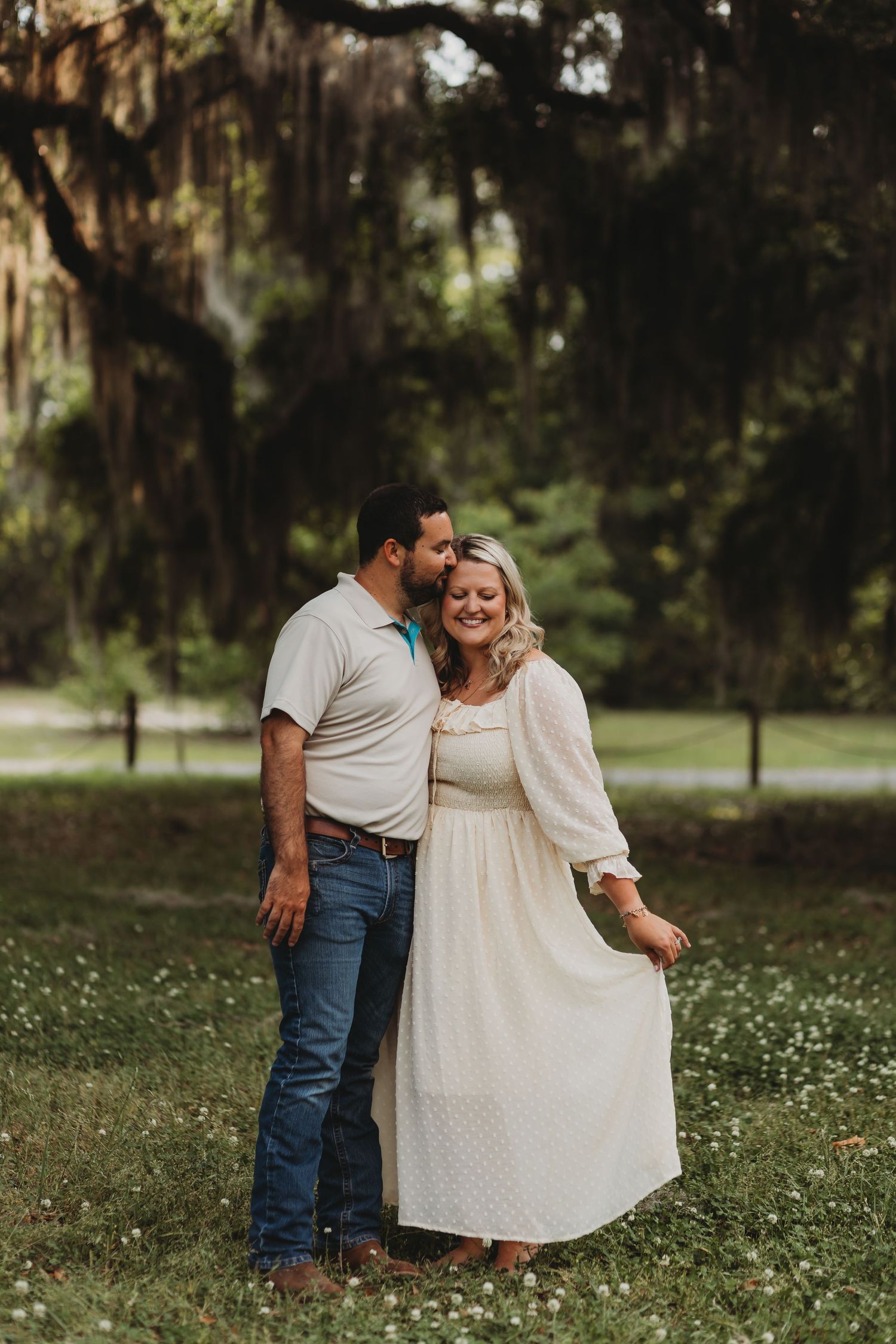 Romantic portrait of a couple embracing in a serene outdoor setting with scattered wildflowers.