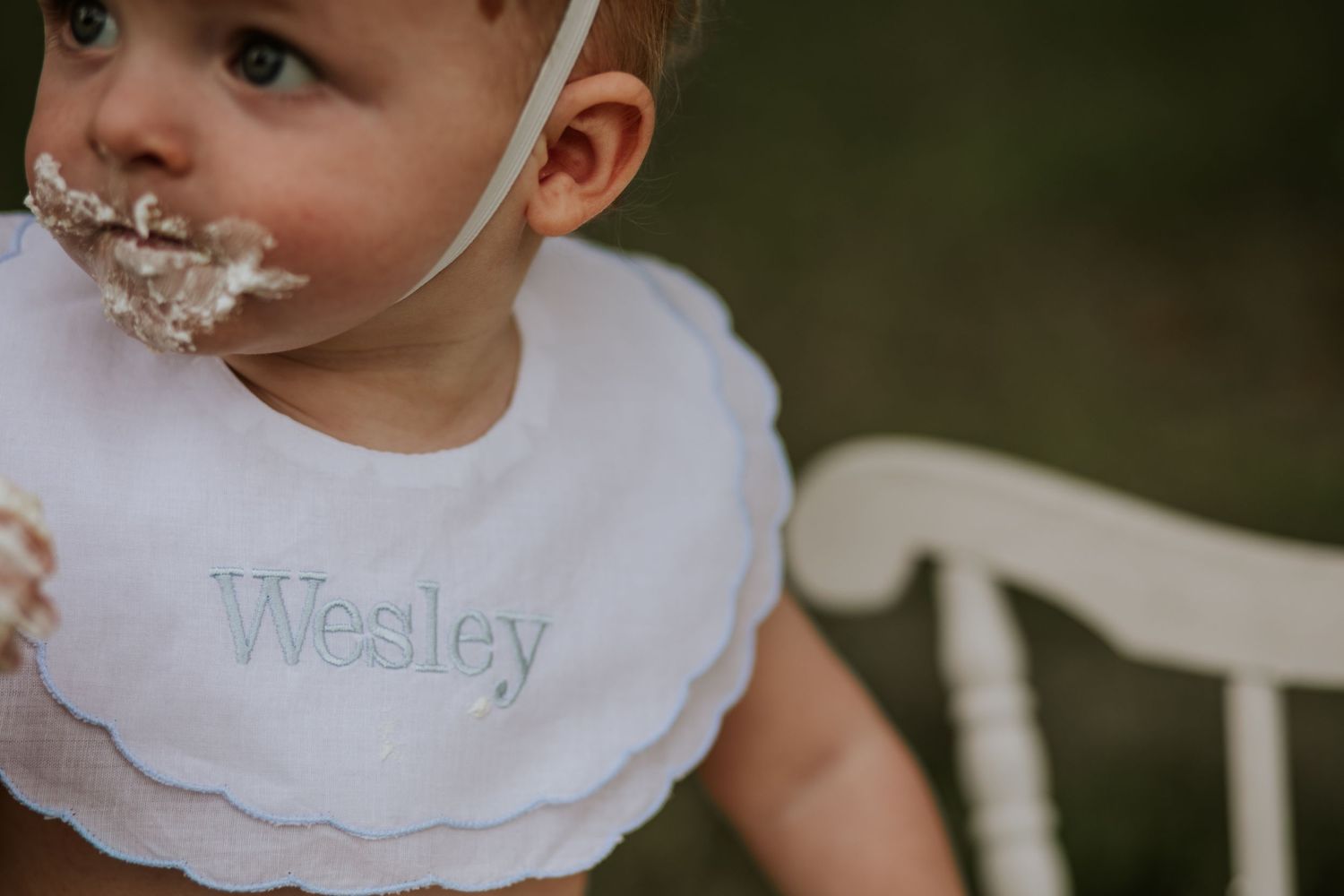 Close up of baby wearing bib with cake frosting on face.