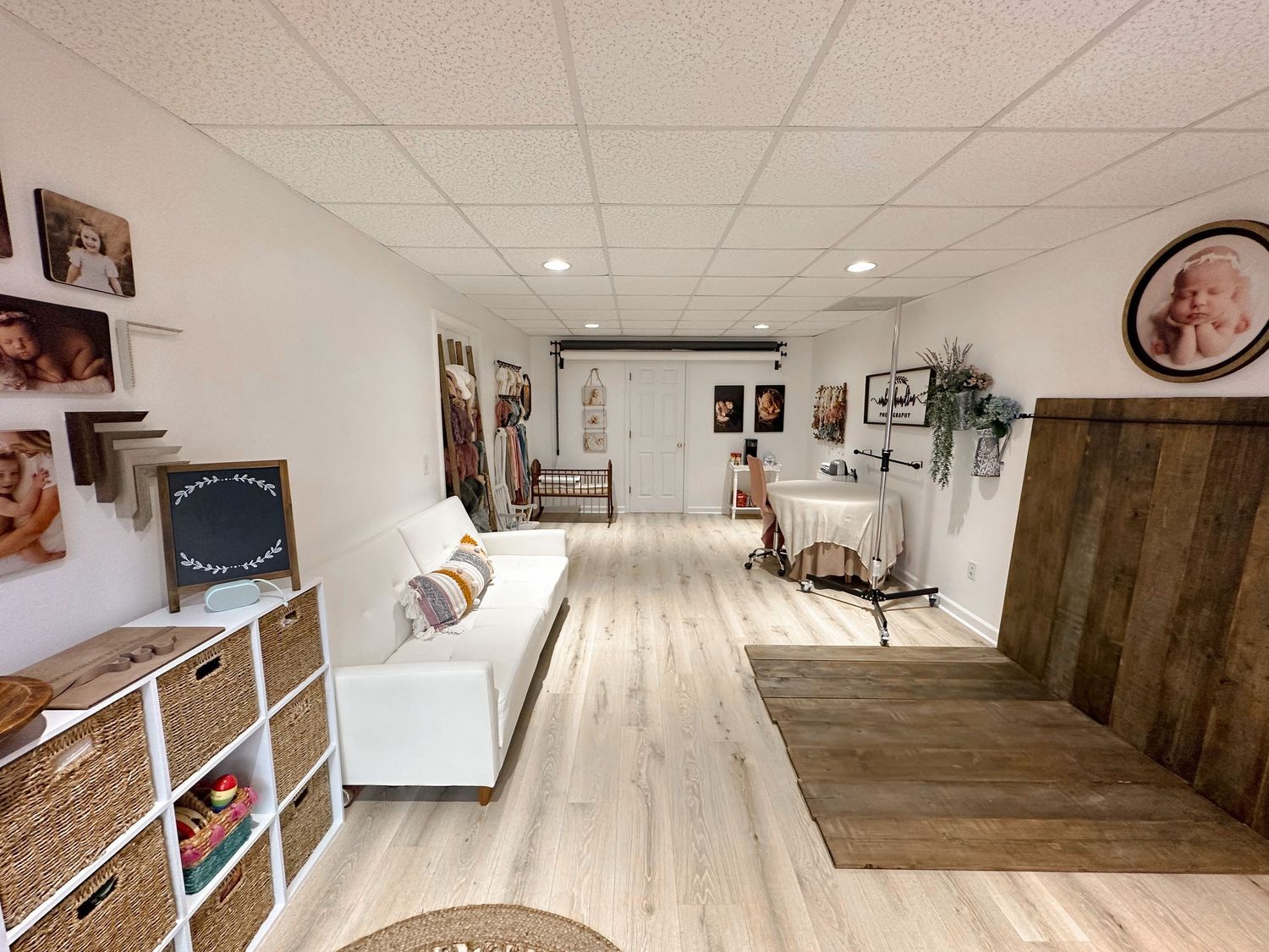 Photography studio interior with white walls, wood floors and portrait display shelves.