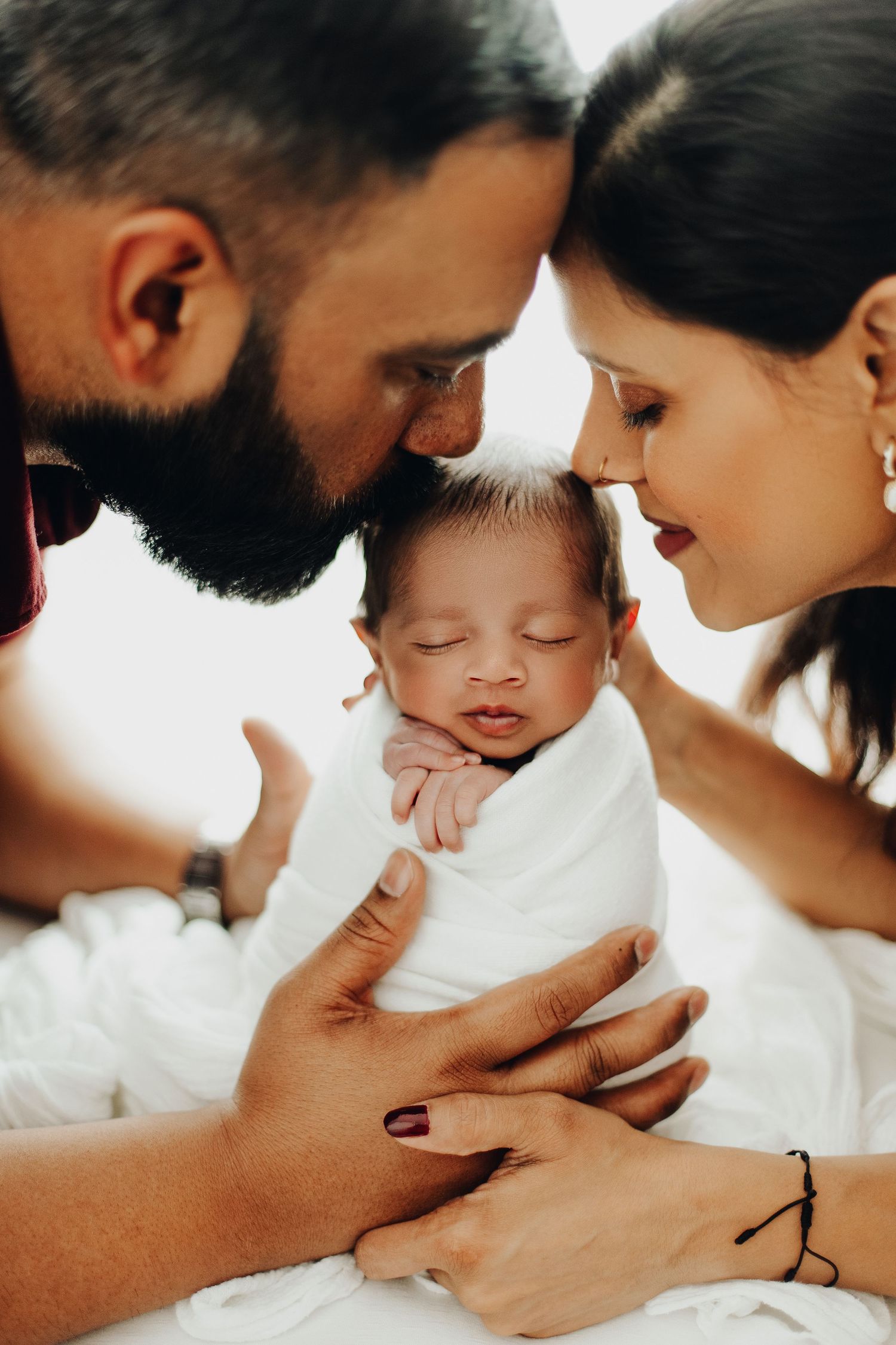 Tender family moment with newborn baby being cradled in soft lighting.