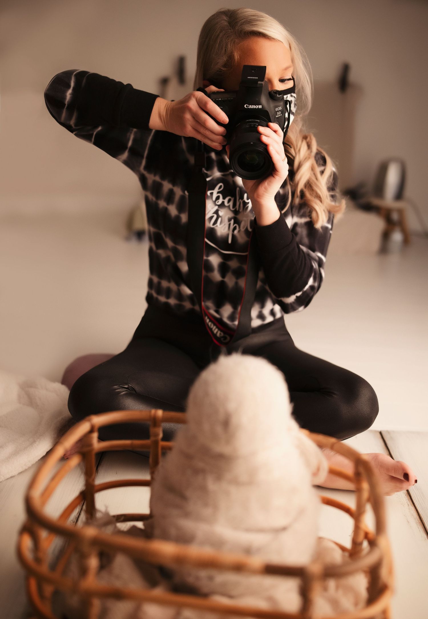 Photographer in plaid shirt taking pictures with professional camera in studio setting.