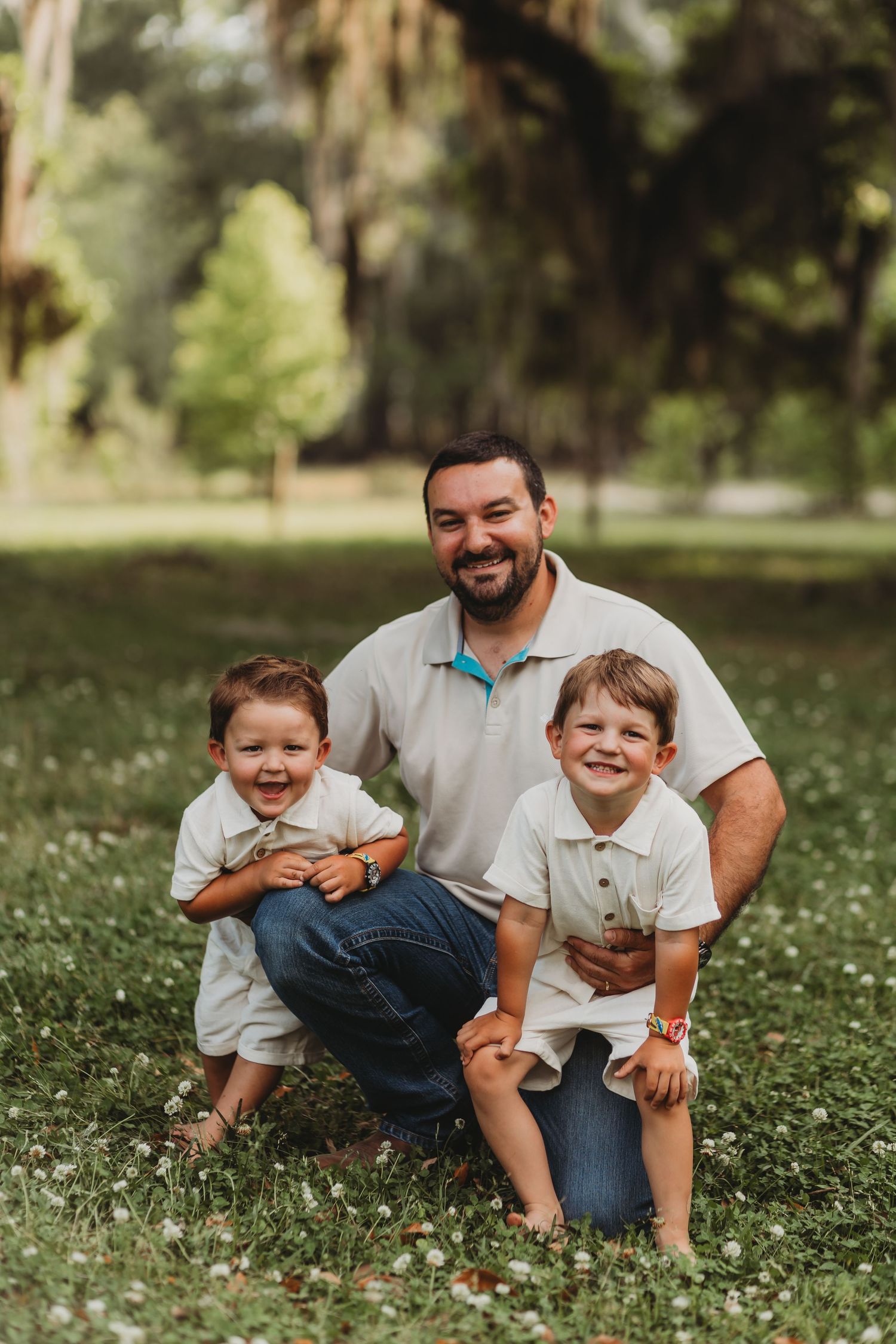 Family portrait of loved ones kneeling together on grass with blooming wildflowers.