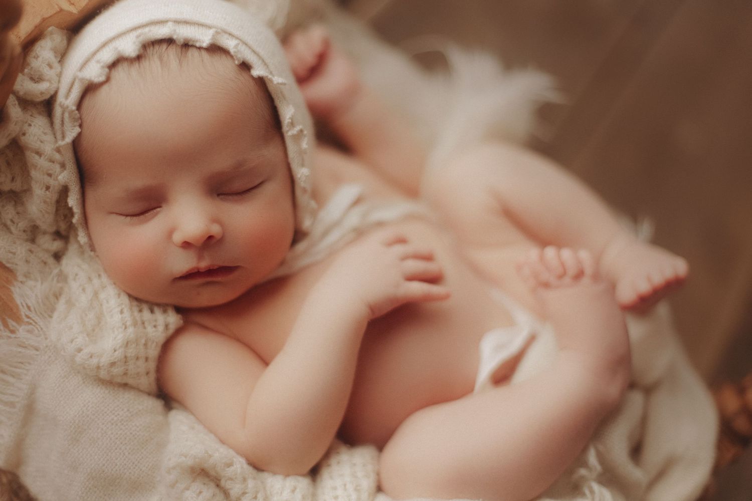 Peaceful newborn sleeps during professional photography session with lace details.