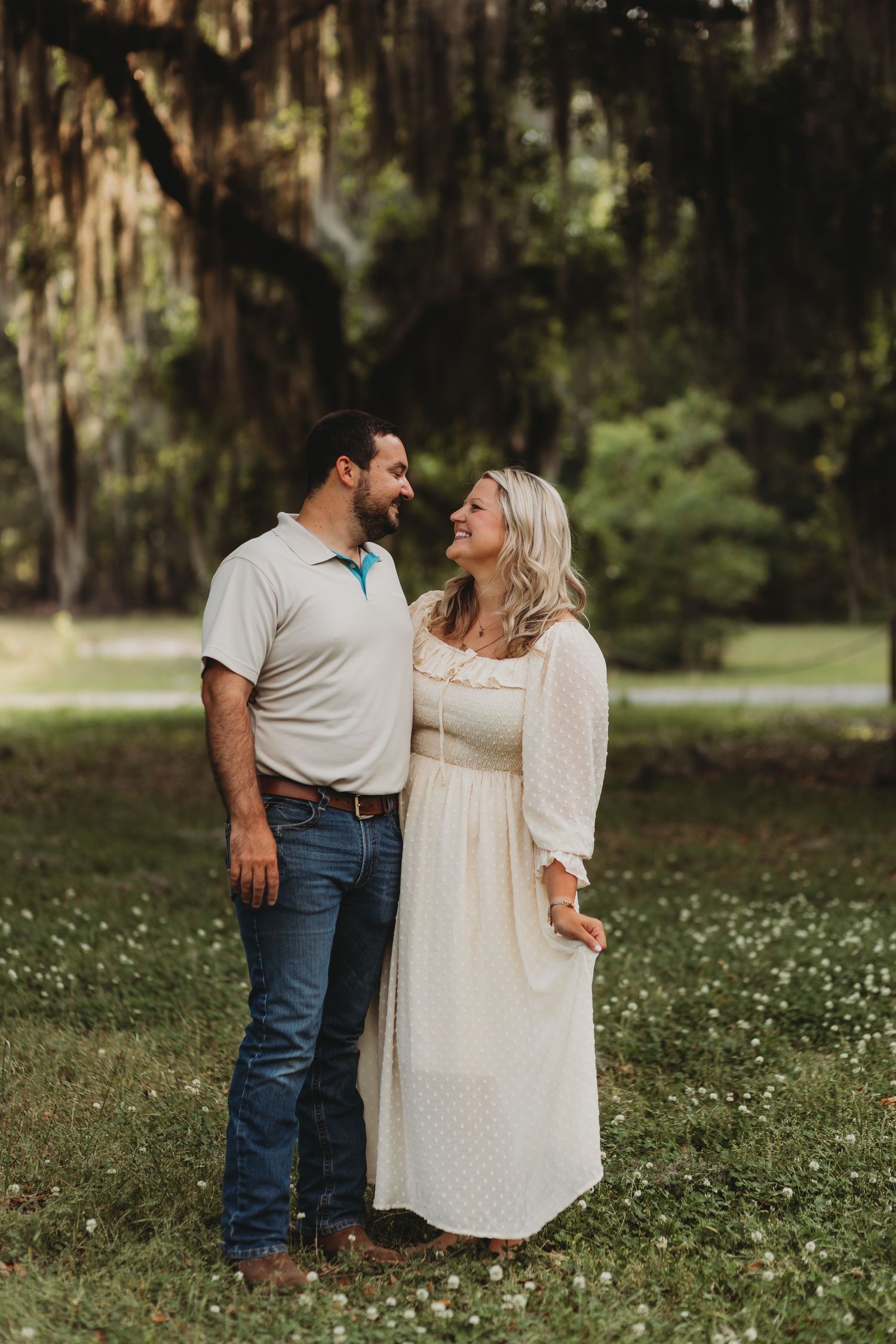 Couple stands lovingly together in a dreamy garden setting with Spanish moss overhead.