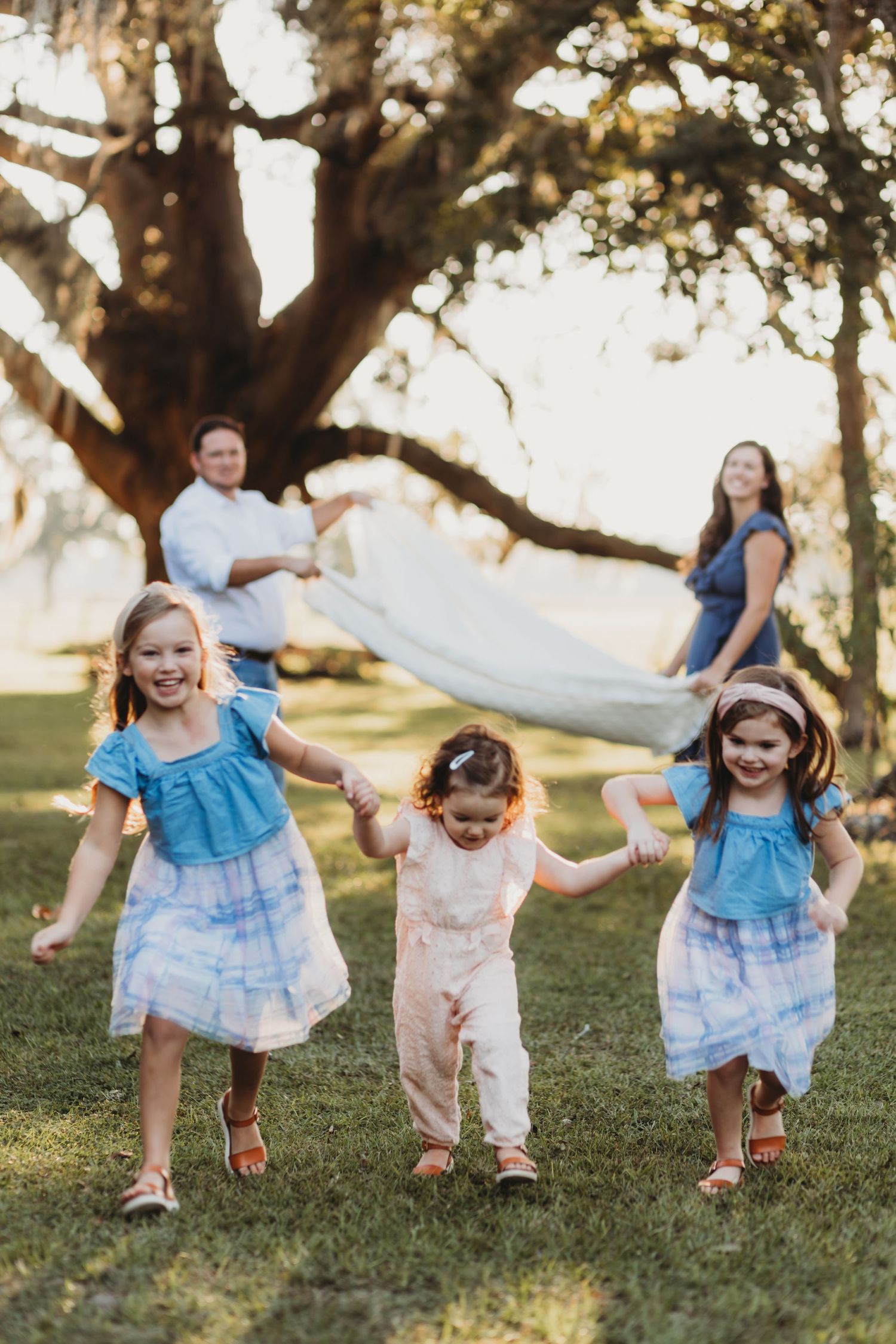 Children playing and running together on grass during sunset outdoor photo session.