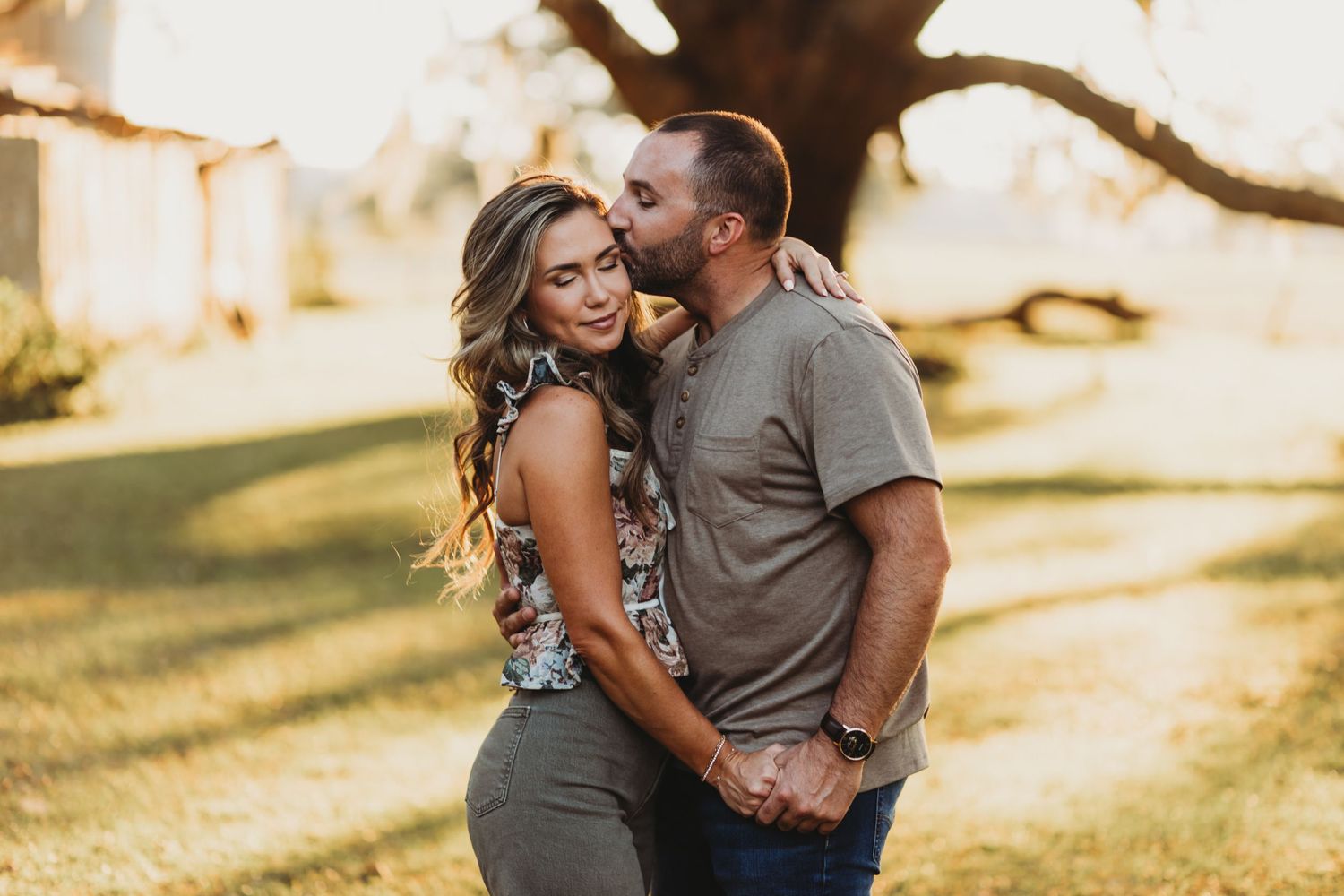 Family photo session in a park during golden hour showing affectionate moments and warm embraces.