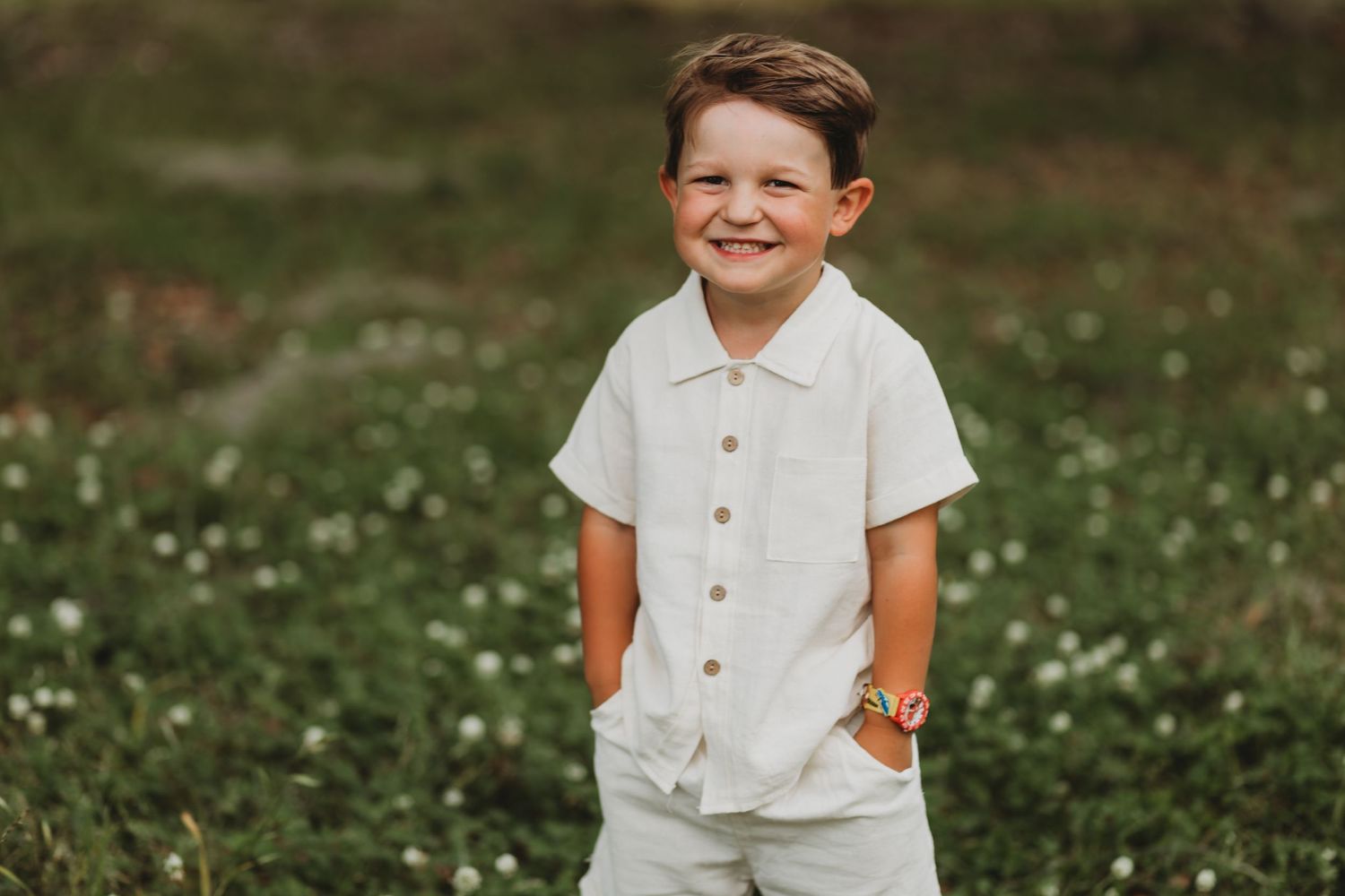 Young person in white outfit stands confidently in a field of wildflowers.