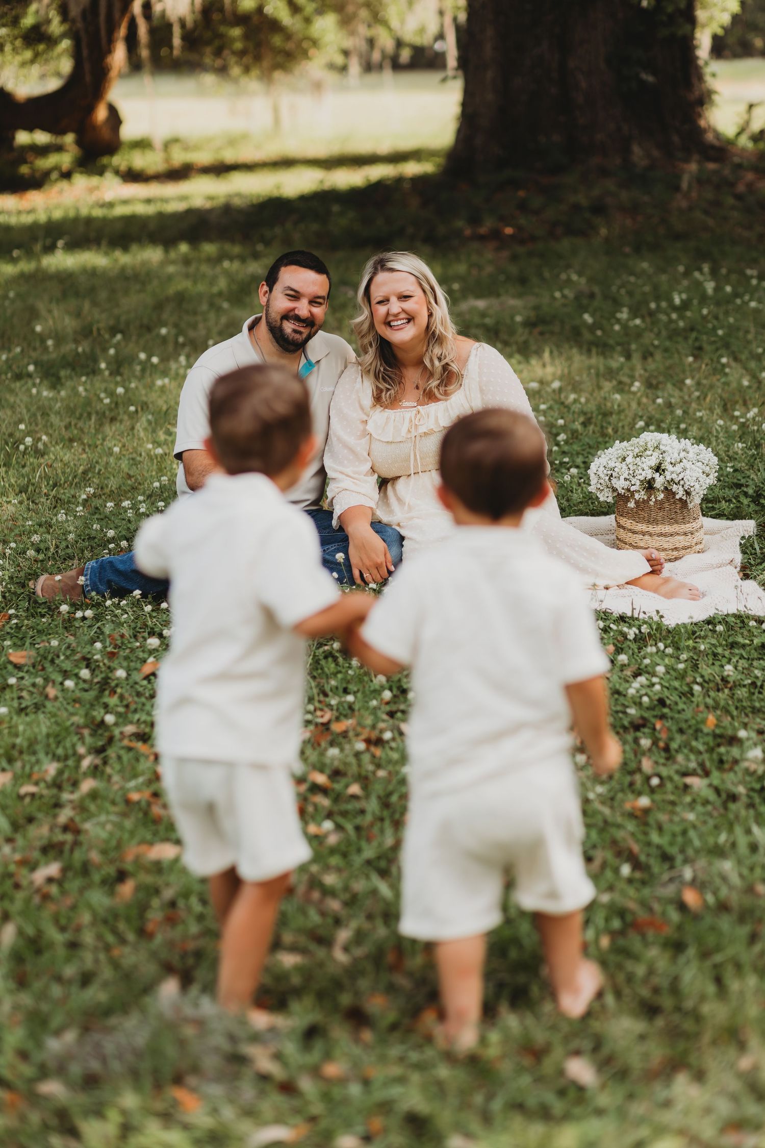 Children in white outfits run towards parents during candid outdoor family photo session.