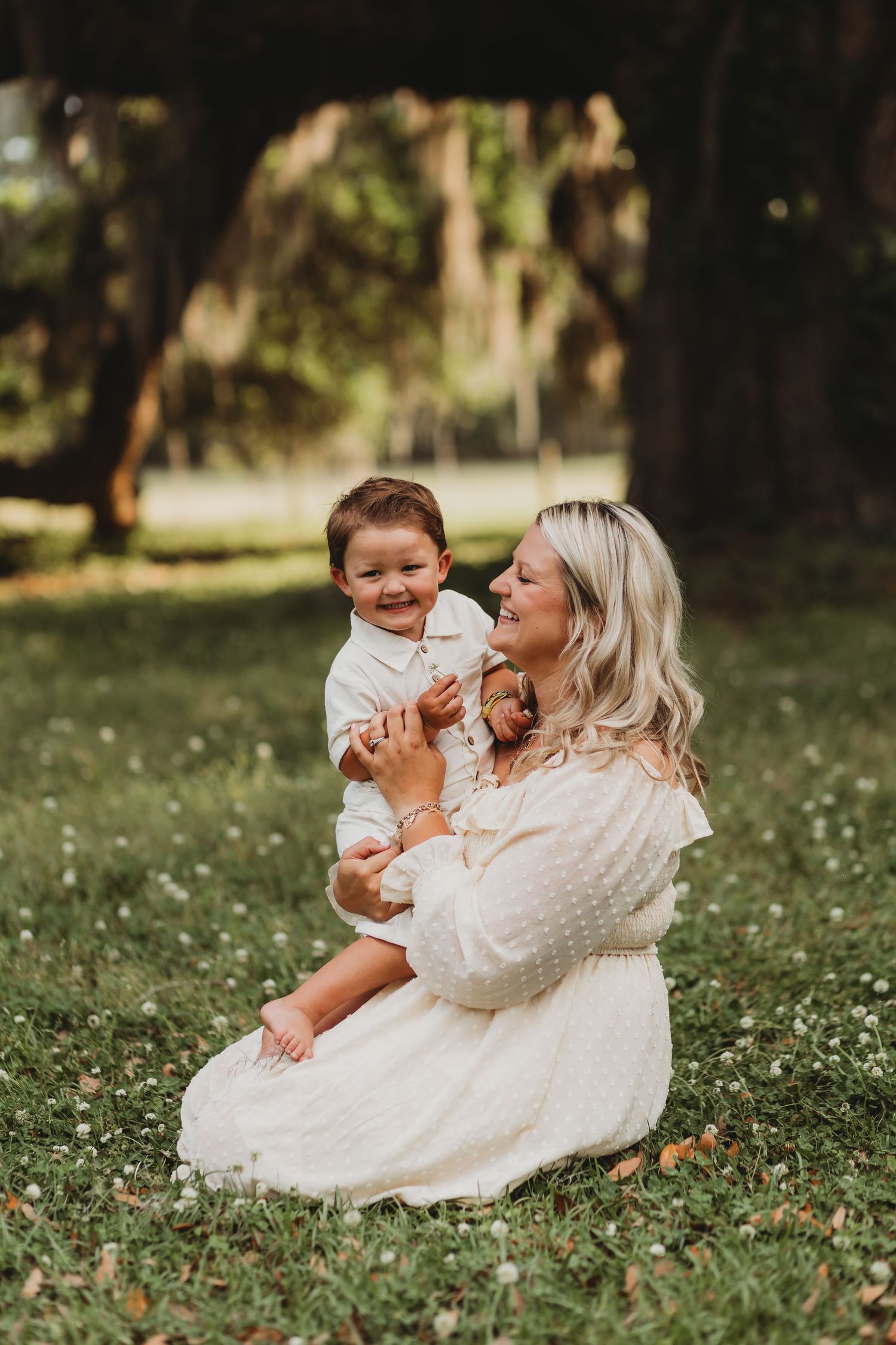 Parent and child share a joyful moment together while sitting in a flower-filled meadow.