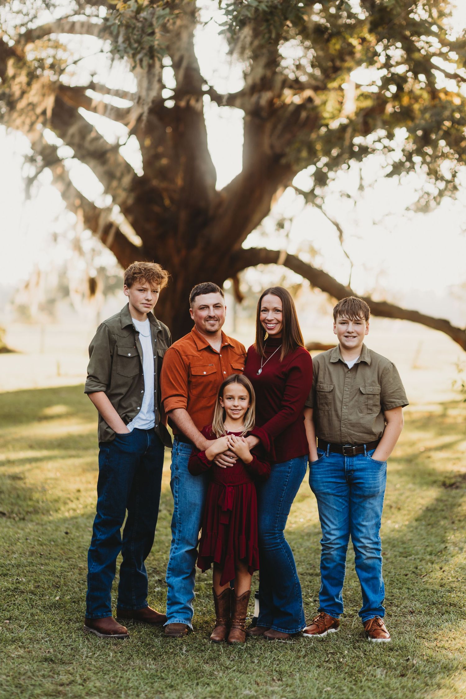 Outdoor family portrait beneath a large oak tree during golden hour.
