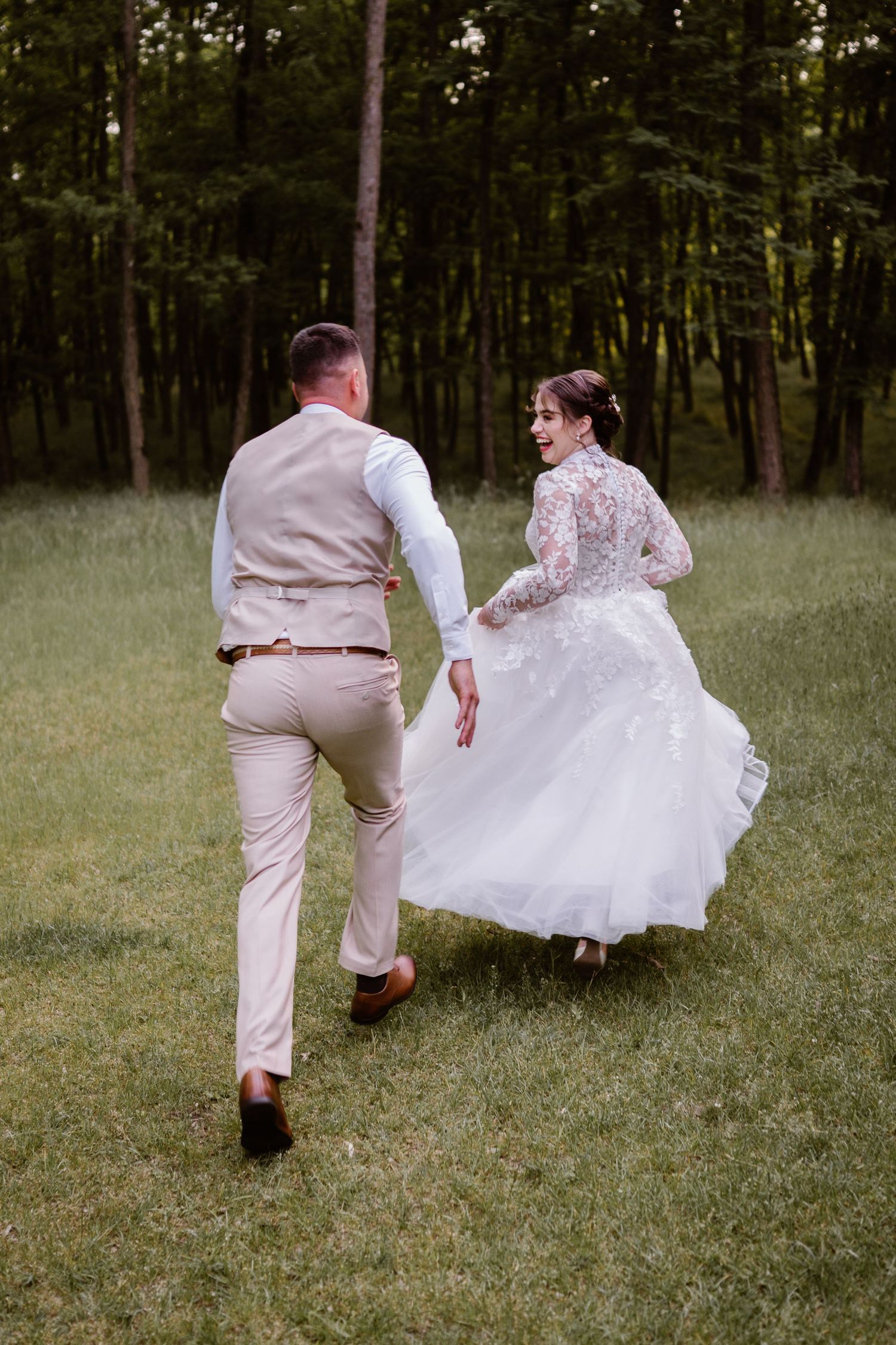 Playful sequence of a couple running and dancing in a grassy field wearing wedding attire.